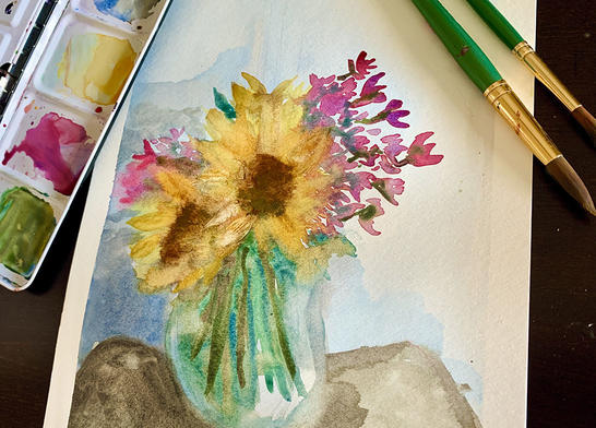 Studio image of a watercolor painting of sunflowers, paints, and brushes.