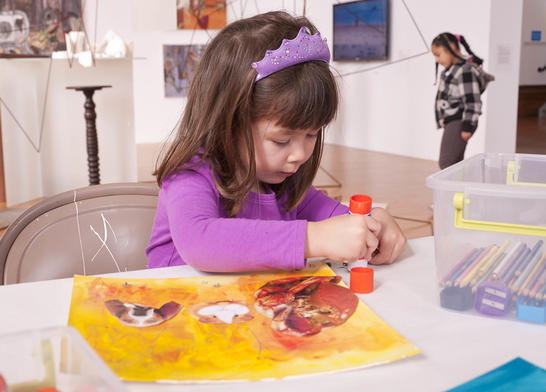 Young girl make a yellow collage using a glue stick