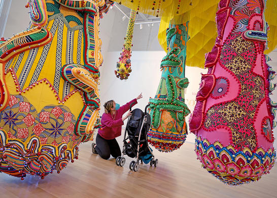 Visitor with a stroller looking up and pointing at the Valykyrie Mumbet sculpture.