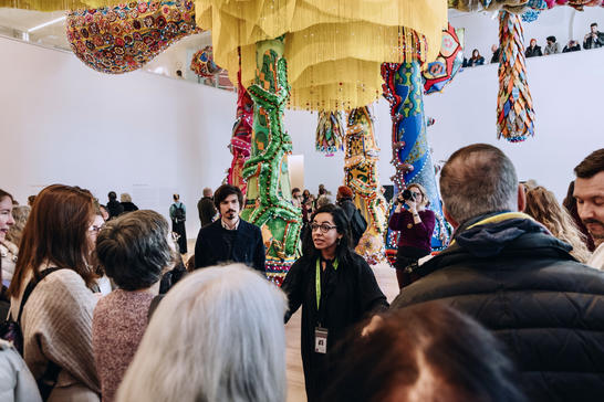 Visitors gather under the site-specific hanging sculpture for a guided tour