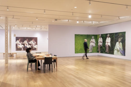 Installation view of visitors in May Stevens exhibition at the Bakalar Gallery at the MassArt Art Museum