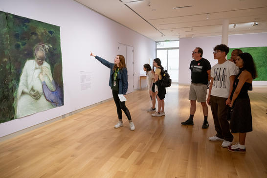 A group of people looking at a painting on the wall