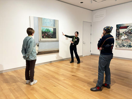 A group of people standing in front of a large painting.