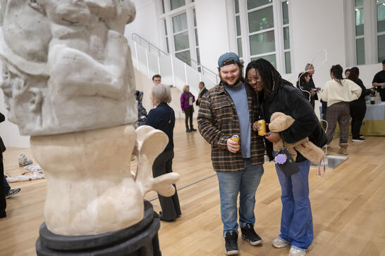 An image of two people holding drinks looking at a sculpture in the Paine Gallery