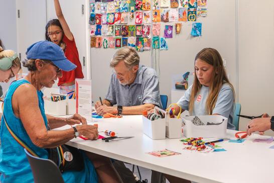 A group of people sitting at a table making art.