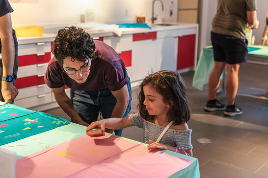 A child, under the supervision of a grown up, makes a block print in the Museum's Barkan Family Big Ideas Studio. 