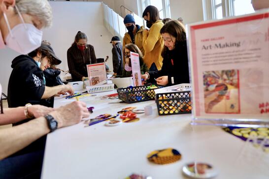 People of various ages sitting around a table, engaged in arts and crafts activities in a bright room.