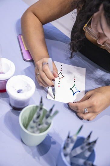 A person uses a water brush pen to paint star shapes on a piece of paper.