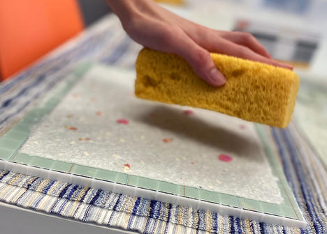 Hand holding a sponge over hand made paper