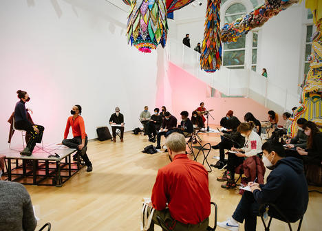 Drawing together event at the museum, showing two figure models, visitors seated while drawing, and a musician in the backgroun.