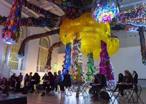 Visitors sketching in low light under the large sculpture by Joana Vasconcelos