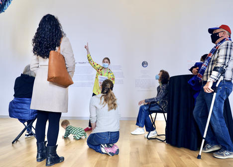 a MAAM educator points at wall text in front of a tour group in the gallery