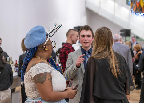 People gather in the gallery in festive attire