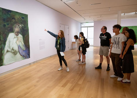 A group of people looking at a painting on the wall