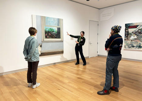 A group of people standing in front of a large painting.