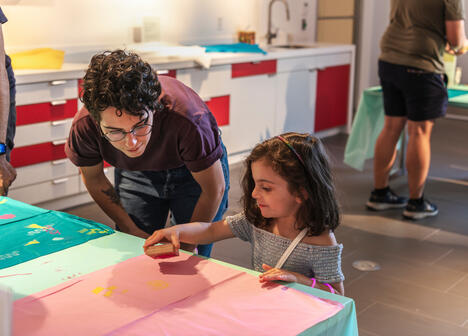 A child, under the supervision of a grown up, makes a block print in the Museum's Barkan Family Big Ideas Studio. 
