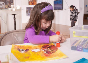 Young girl make a yellow collage using a glue stick