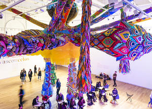 People gather and sketch under Joana Vasconcelos' huge sculptural installation.