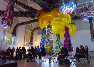 Visitors sketching in low light under the large sculpture by Joana Vasconcelos