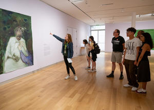 A group of people looking at a painting on the wall