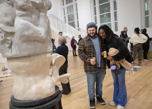 An image of two people holding drinks looking at a sculpture in the Paine Gallery