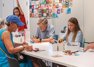 A group of people sitting at a table making art.