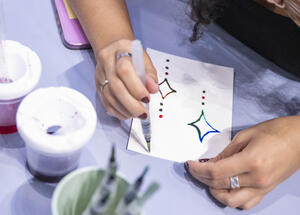 A person uses a water brush pen to paint star shapes on a piece of paper.