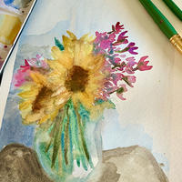 Studio image of a watercolor painting of sunflowers, paints, and brushes.