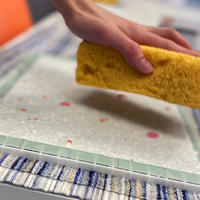 Hand holding a sponge over hand made paper