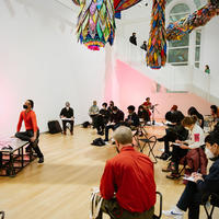 Drawing together event at the museum, showing two figure models, visitors seated while drawing, and a musician in the backgroun.