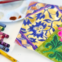 Image of crayons, pencil, eraser, and brightly colored patterns on paper made using ink resist technique