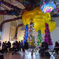 Visitors sketching in low light under the large sculpture by Joana Vasconcelos