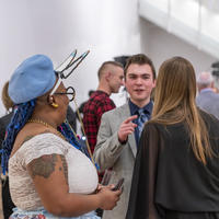 People gather in the gallery in festive attire