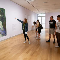 A group of people looking at a painting on the wall