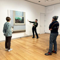 A group of people standing in front of a large painting.