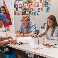 A group of people sitting at a table making art.