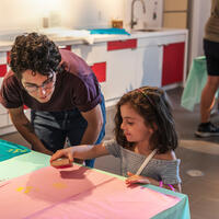 A child, under the supervision of a grown up, makes a block print in the Museum's Barkan Family Big Ideas Studio. 