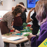A woman demonstrates an art project to a group; CANCELED is written diagonally across the image.