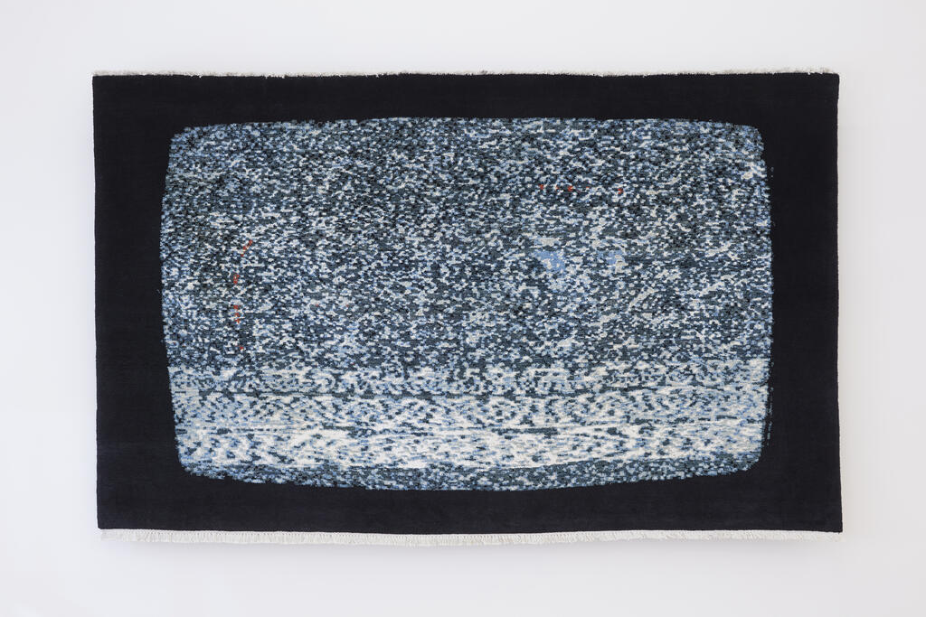 A woven rug with the image of a fuzzy, snowy tv that has lost signal