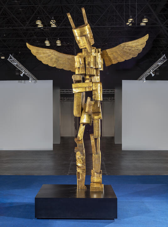 Large bronze totem pole in multiple pieces with an eagle's head and outstretched wings