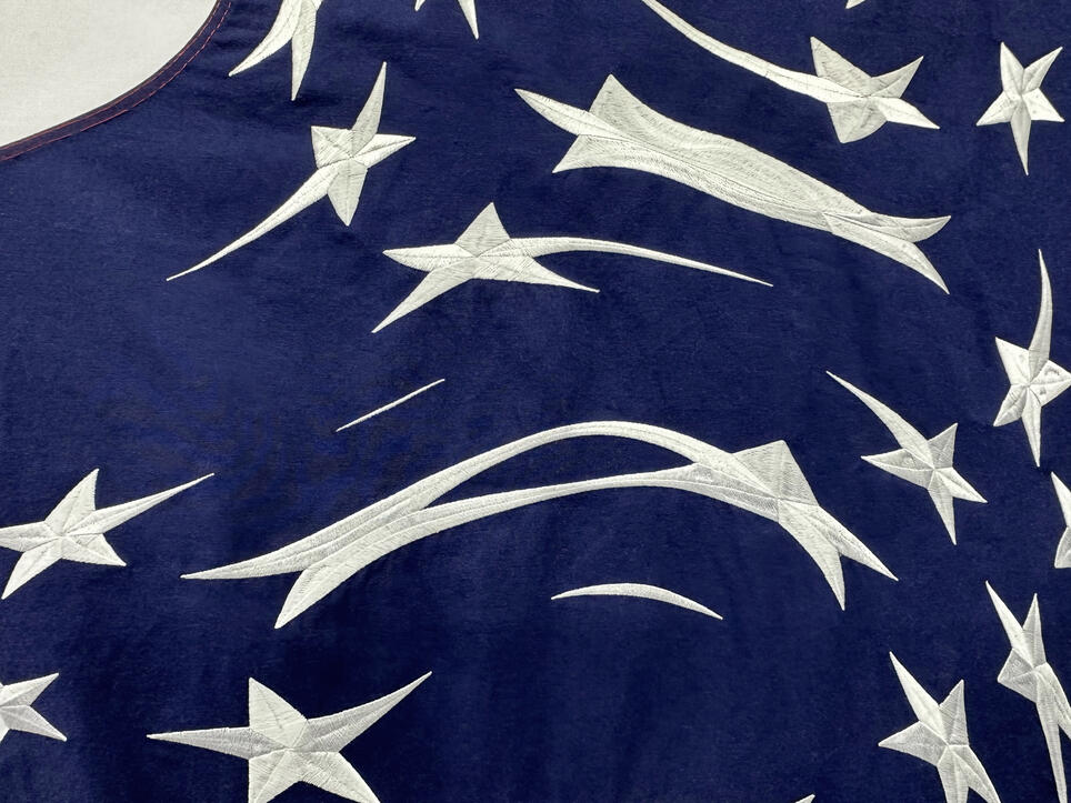 Navy blue fabric with white embroidered shooting stars and abstract curved shapes scattered across the surface.