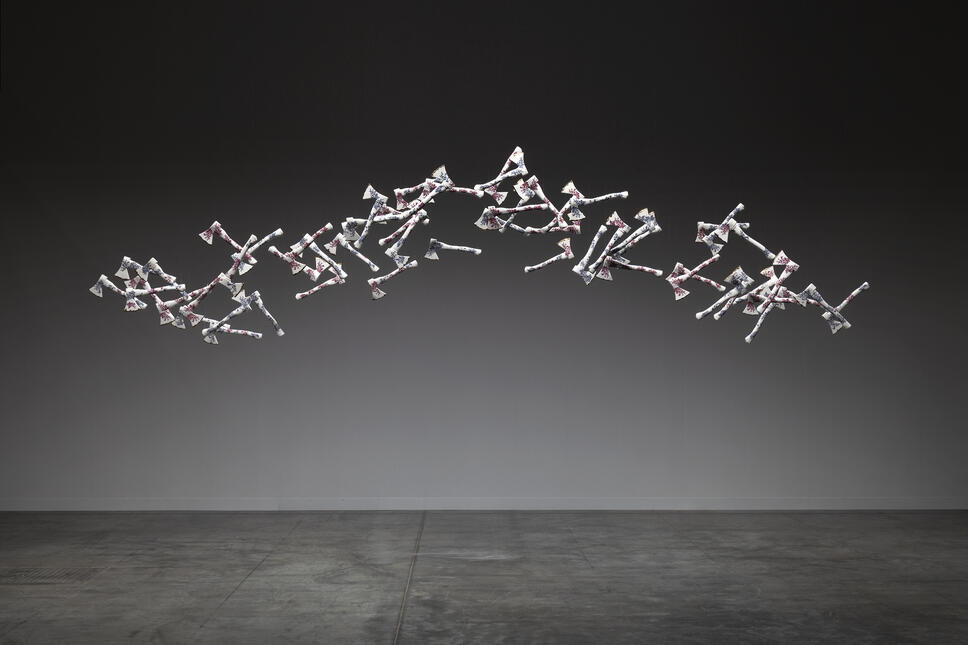 60 porcelain hatchets, white with floral pattern, suspended in an arc on a dark background