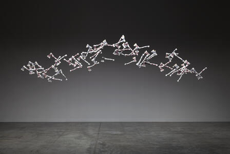 60 porcelain hatchets, white with floral pattern, suspended in an arc on a dark background