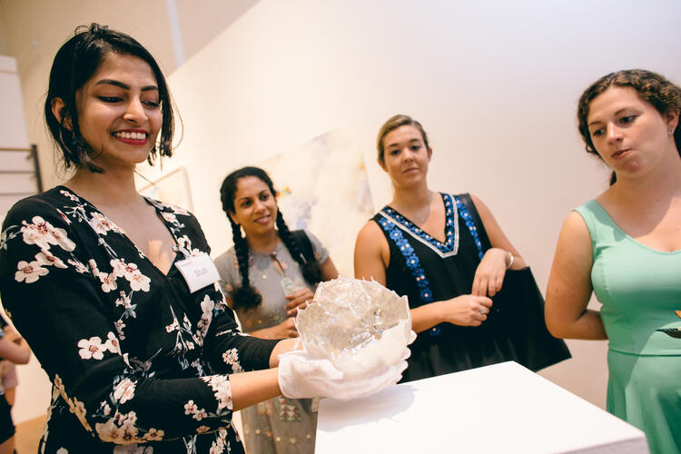 Gallery attendant wearing white gloves handles piece.