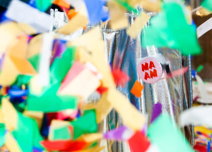 Colorful confetti surrounds a pin with MAAM's logo